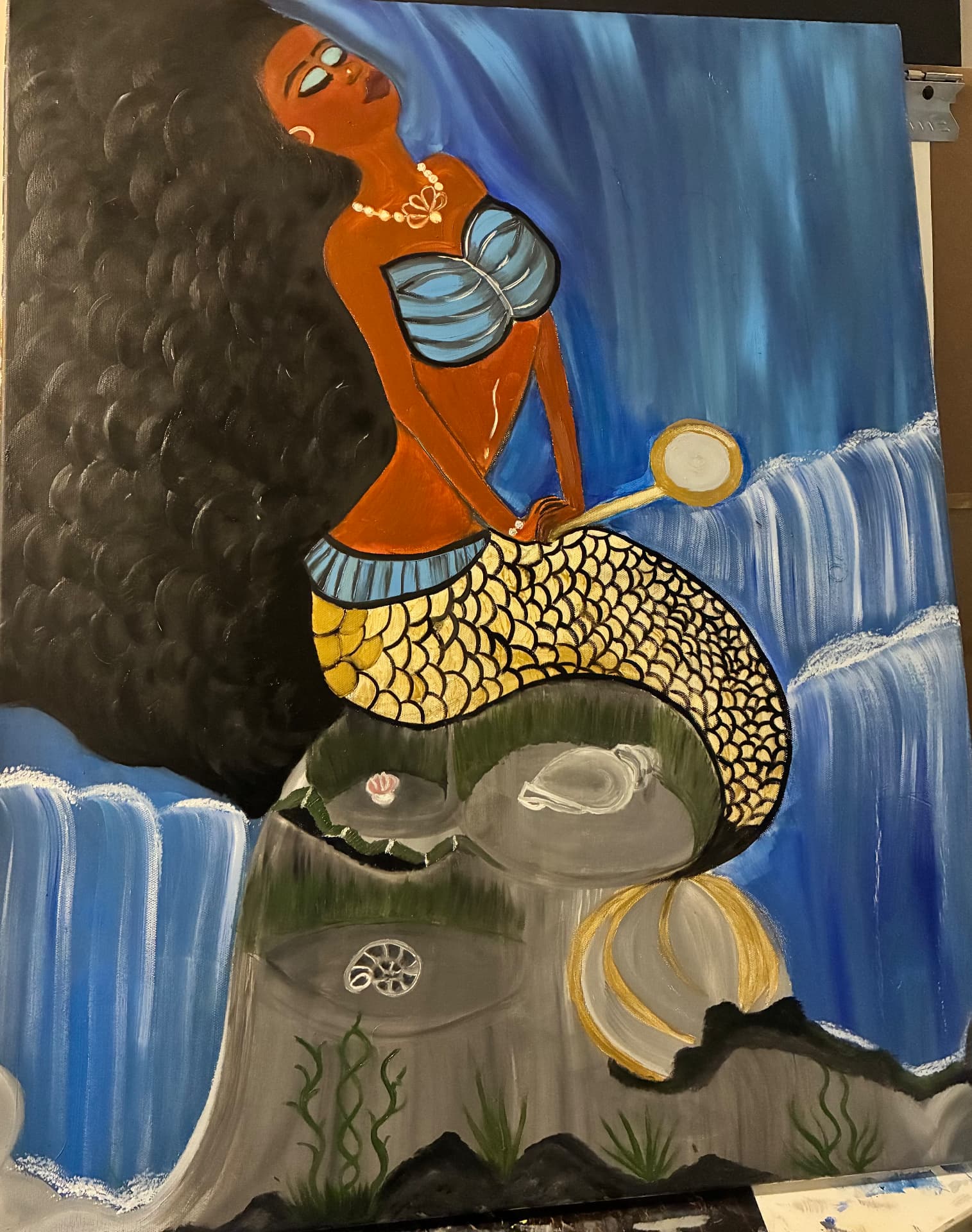 A mermaid figure with a hand mirror seated above a waterfall